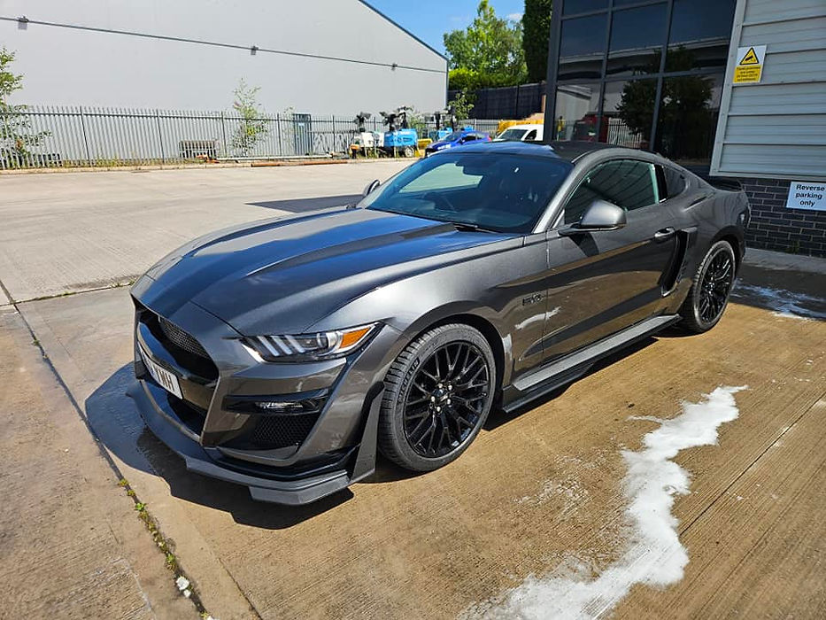 A sleek gray Ford Mustang Shelby GT500 sports car with black wheels, freshly washed and gleaming in the sun