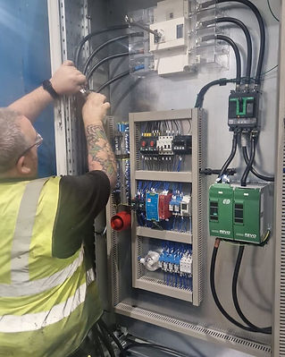 Electrician working on wiring inside an electrical control panel