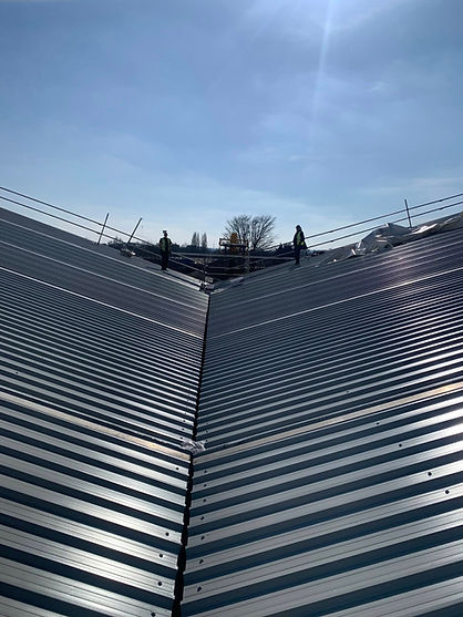 Metal roof panels form a V-shape under a clear blue sky
