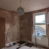 A room being renovated, with plastered walls and ceiling
