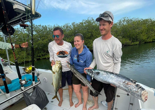 3 People posing with alot of fish in a boat Placencia