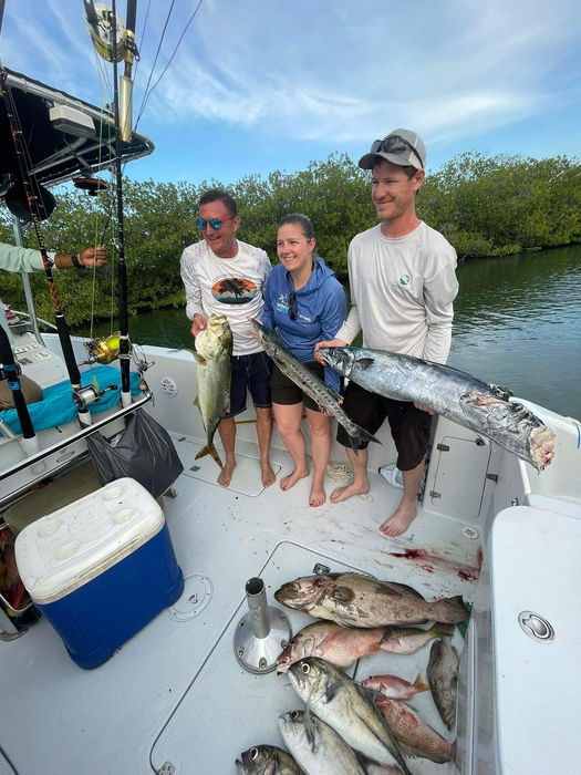 3 People posing with alot of fish in a boat Placencia