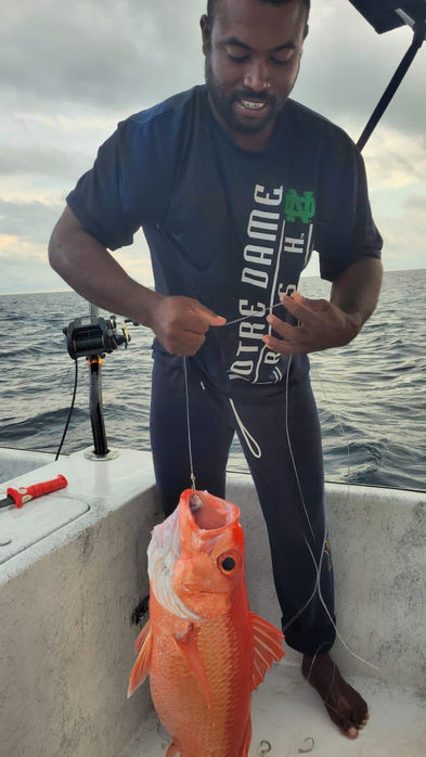 Guy Holding red snapper by fishing line  Placencia