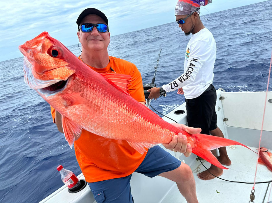 Guy Holding Red Snapper in a boat Placencia