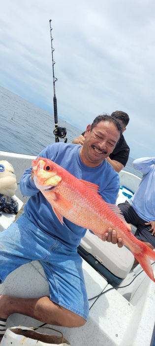 Guy holding red snapper in a boat Placencia