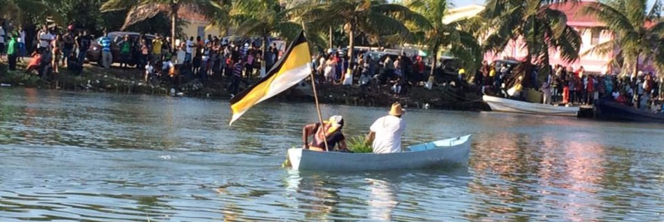two men in small dorey on river garifuna settlement day re-enactment in dangriga belize