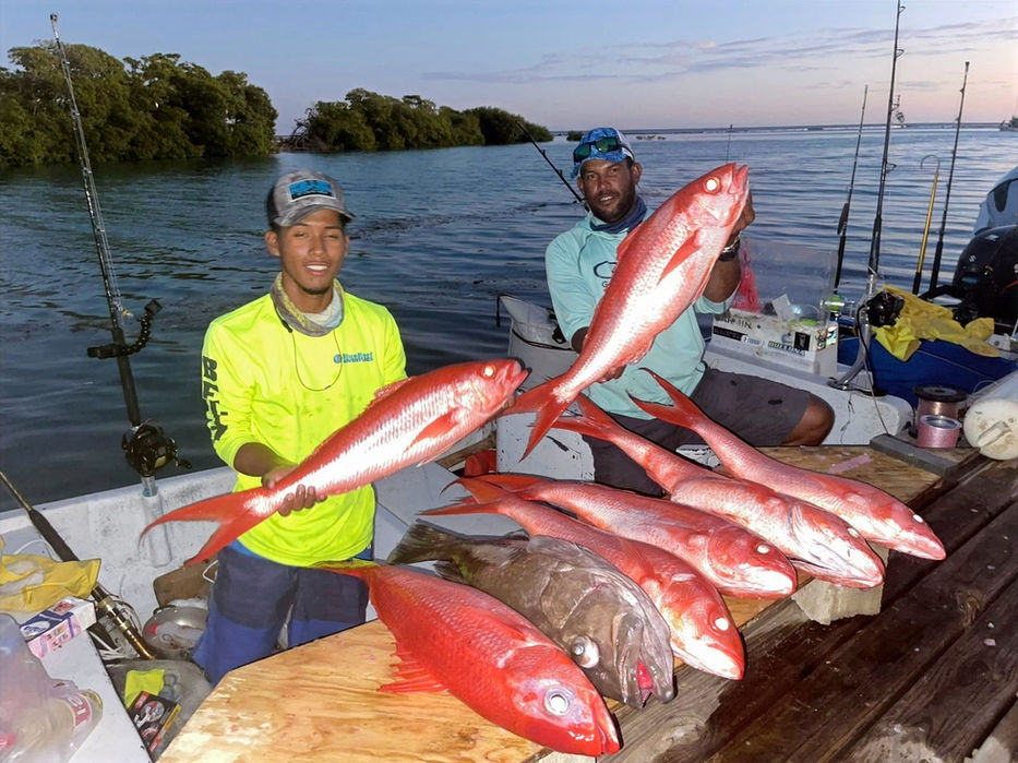 Two guys holding red snapper in boat Placencia