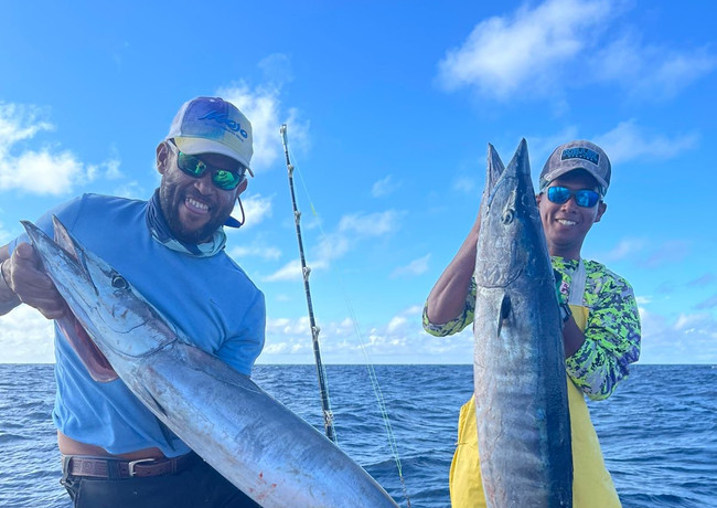 Two Men holding Two fish in a boat Placencia