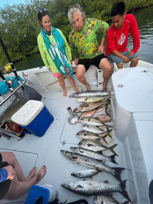 3 People posing with alot of fish in a boat Placencia