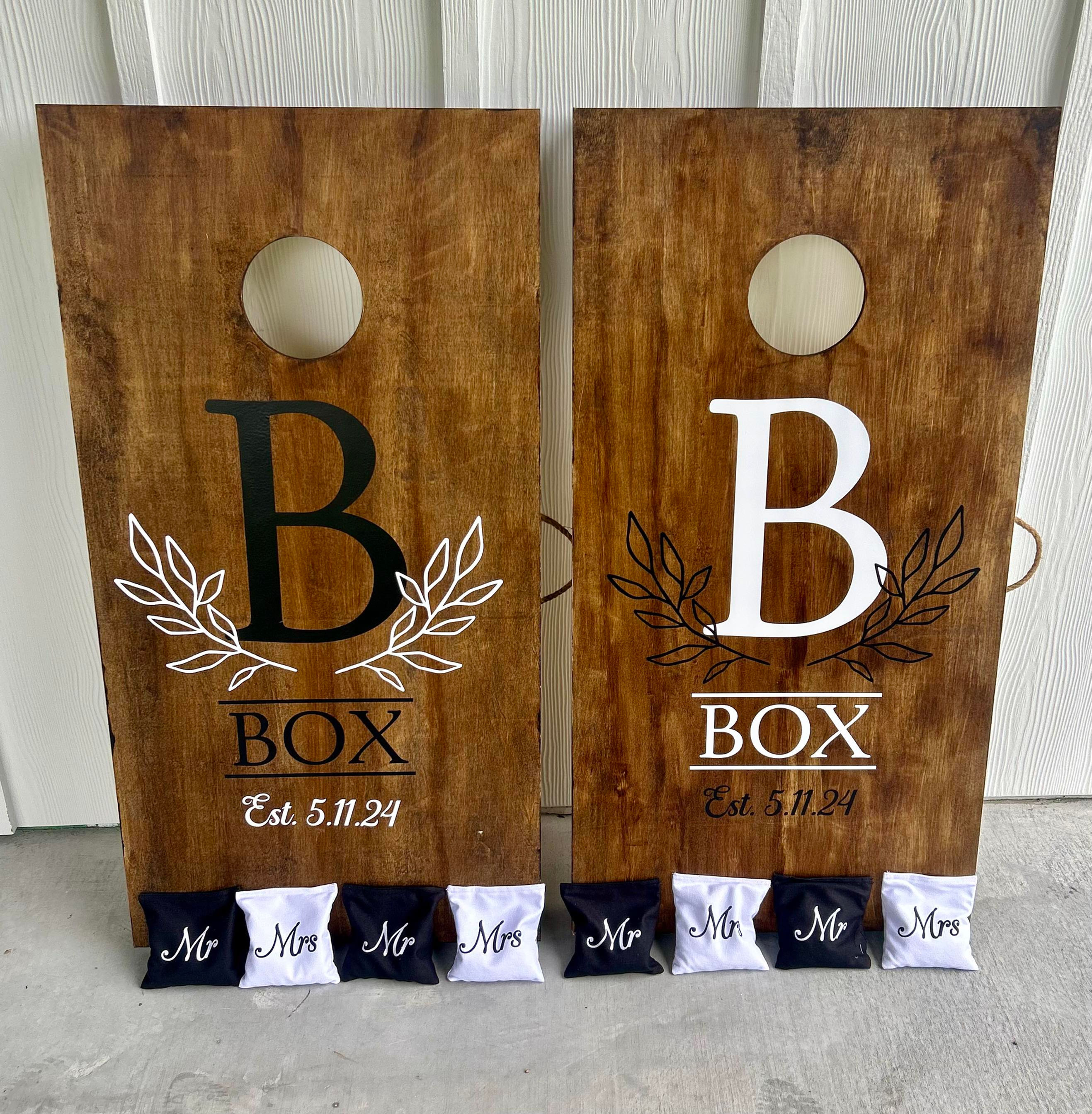 Two custom cornhole boards with the letter B, BOX, and Est. 5.11.24
