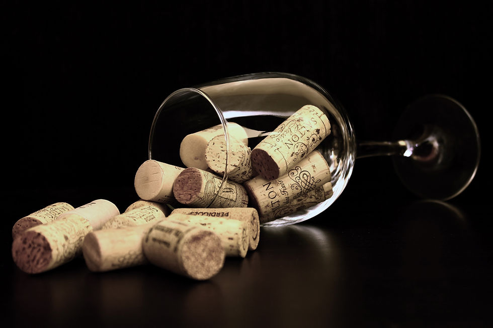 Wine corks spill from a tipped wine glass on a dark surface. Corks feature varied lettering and designs, creating a rustic, artistic vibe.