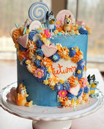 Bluey and Bingo cake with colorful frosting, lollipops, and 'Autumn' text.