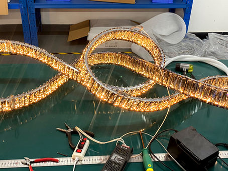 Crystal chandelier fixture on a workbench undergoing its first light-up test, showcasing the initial illumination during Luminance Innovations’ quality control process.