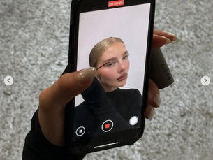 Mujer mirándose al celular mientras se arregla