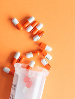 Prescription drugs on an orange background with a pill bottle. Orange pills_edited.jpg