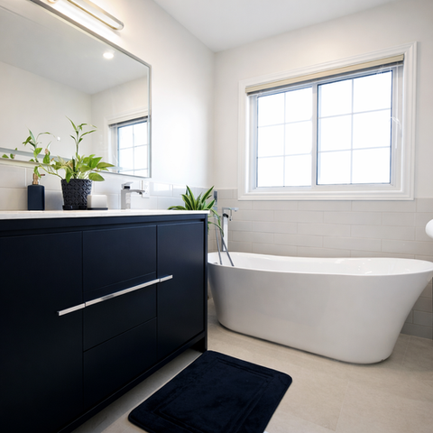 Bathroom renovation with freestanding tub, dark vanity, and bright window