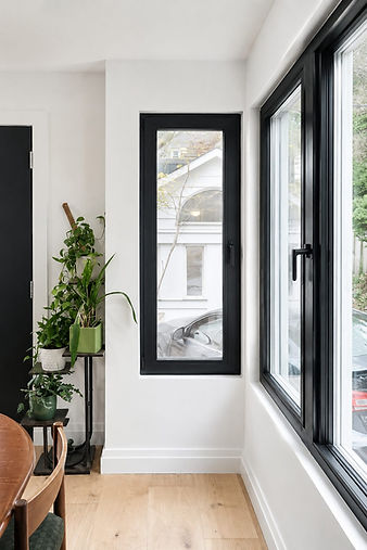 Modern black frame windows in a renovated room with plants.