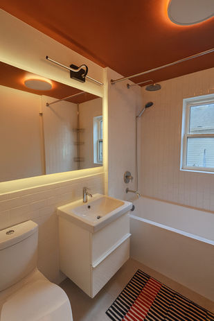 Bathroom renovation with bathtub, vanity, and warm accent ceiling