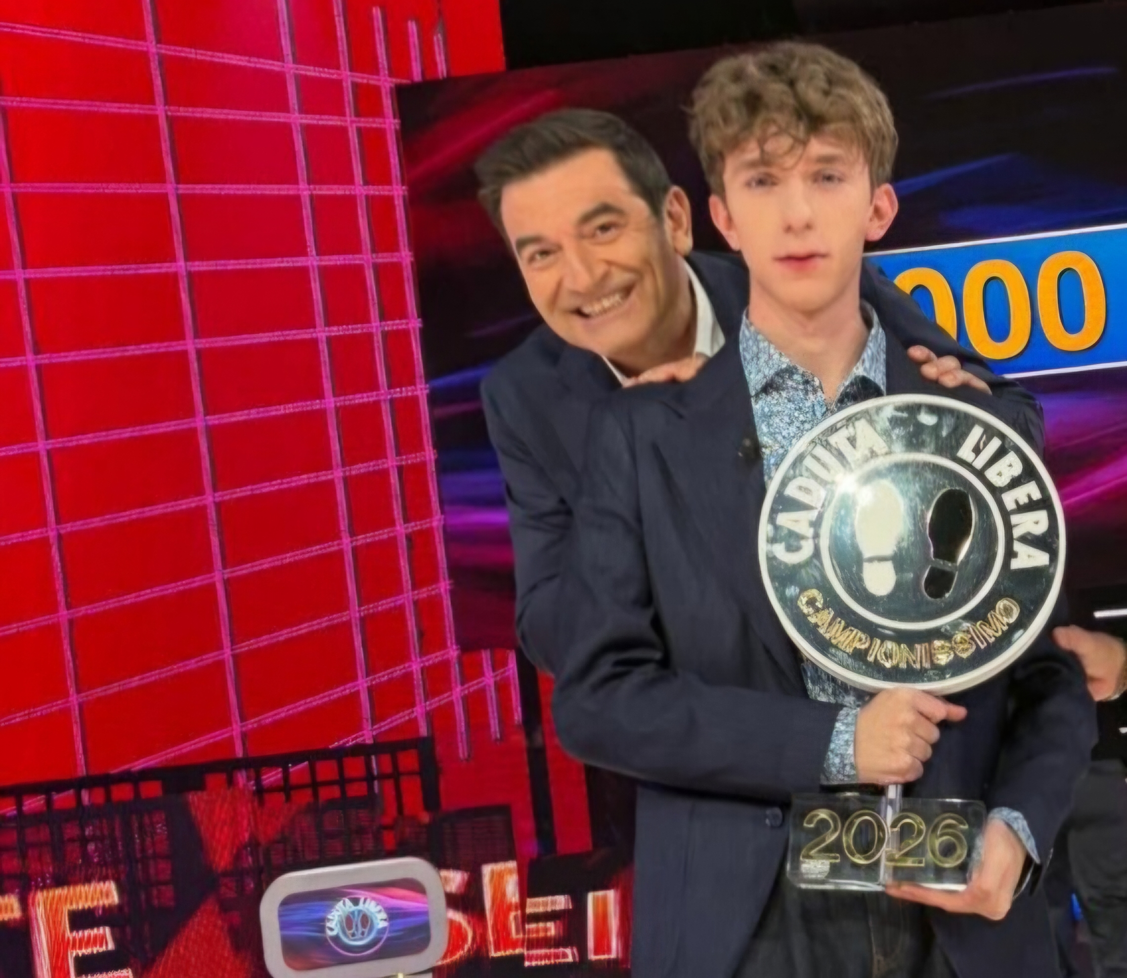 Riccardo, emozionato, mostra il suo meritato trofeo accanto al presentatore Max Giusti.