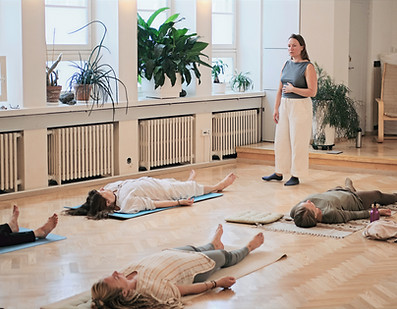 Feldenkrais-ryhmätunnin osallistujat lepäävät selinmakuulla alustoillaan aistien omaa kehoaan
