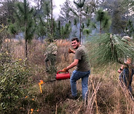 Ian Goldberg is a white man with short straight brown hair and a beard. He is wearing a gray t-shirt, jeans, and brown work gloves.