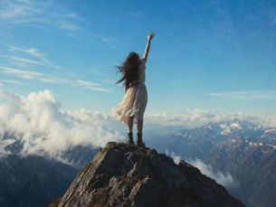 A woman on top of a mountain reaching for the sky 