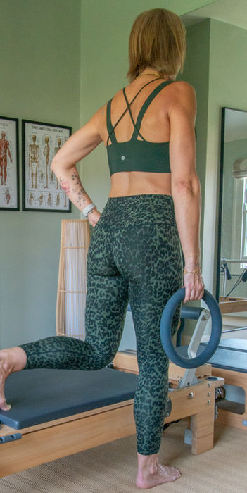 Woman doing Pilates with a weight on reformer