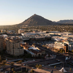 Aerial view of a cityscape with commercial buildings in the foreground and Camelback Mountain in the background.