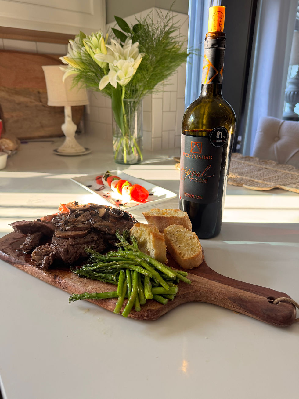 A ribeye steak with mushrooms, roasted asparagus and garlic crostini with a caprese salad