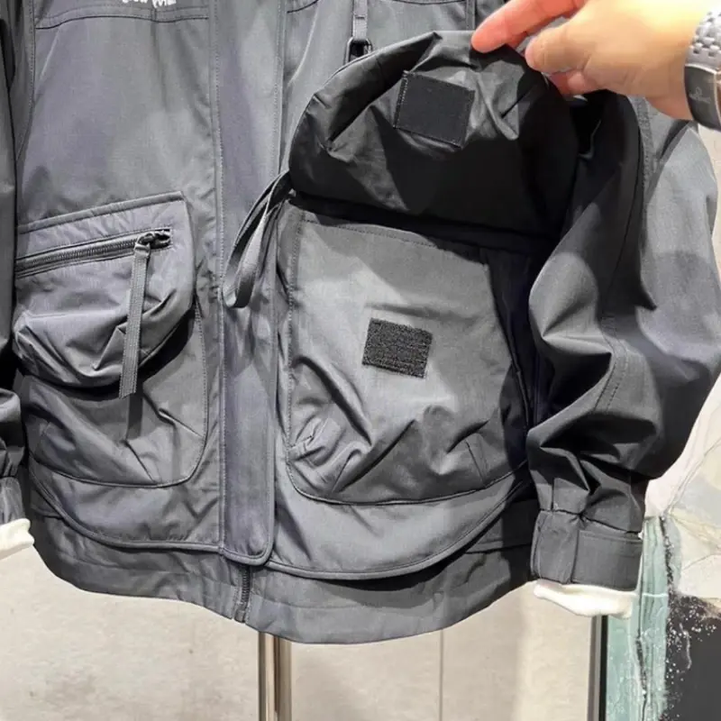 Thumbnail: Hand opening large pocket on dark grey jacket