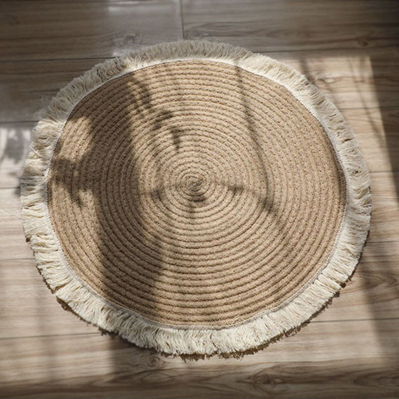 Round woven rug with fringe on a wood floor