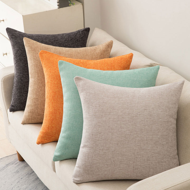 Five sofa cushions in gray, beige, orange, teal, and oatmeal colors