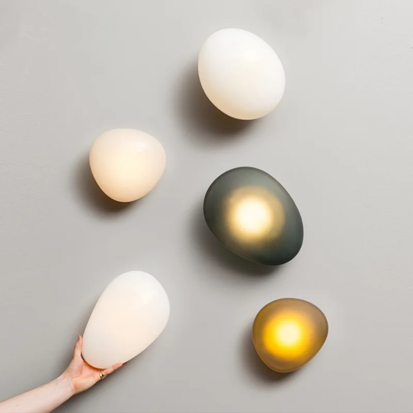 Thumbnail: Five colorful Nordic egg-shaped wall lamps, one held by a hand