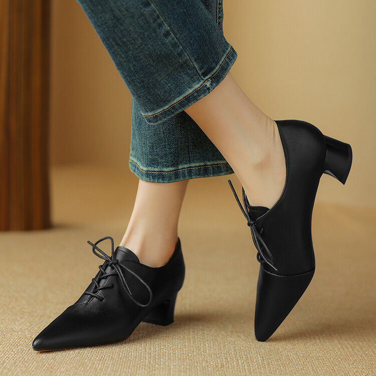 Thumbnail: Person wearing black lace-up pointed-toe shoes