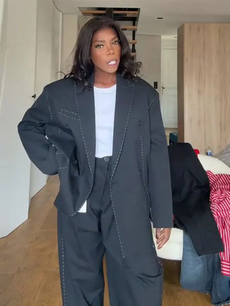 Thumbnail: Woman in black oversized suit with white stitching