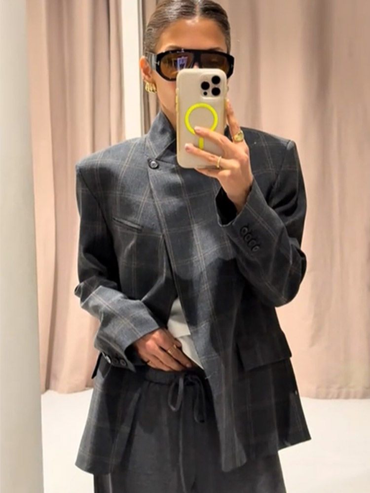 Thumbnail: Person in grey plaid asymmetric blazer taking mirror selfie