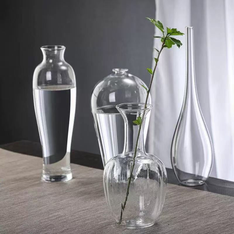 Clear glass vases, one with a green stem, on a table