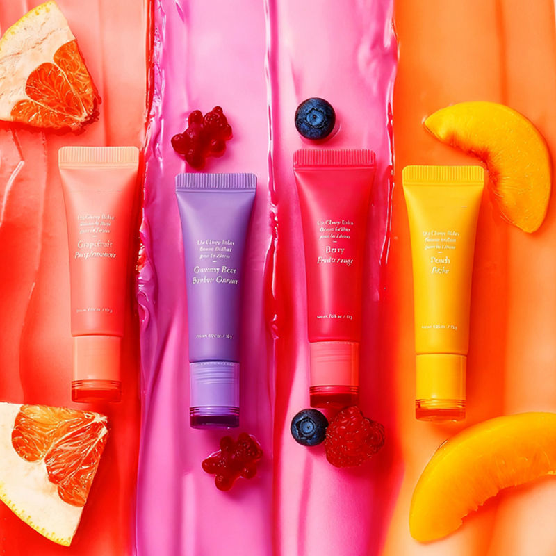 Colorful lip gloss serum tubes with grapefruit, berries, mango