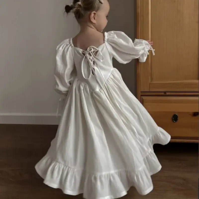 Child spinning in white dress with laced back