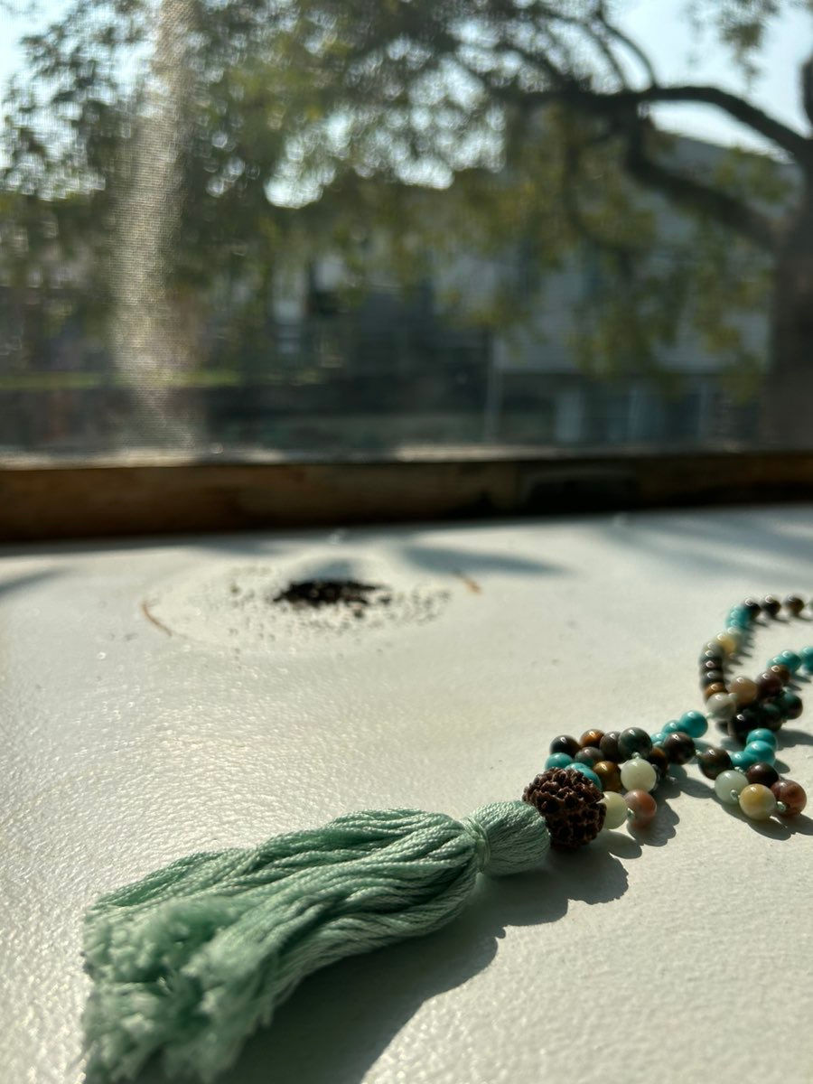 A mala necklace sitting in a sunny window sill