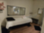 Elegant and serene massage room at Lily Skin & Body Care in North Vancouver, featuring a neatly prepared massage table, a full-length mirror, soft lighting, and delicate floral accents to create a calming and inviting environment.