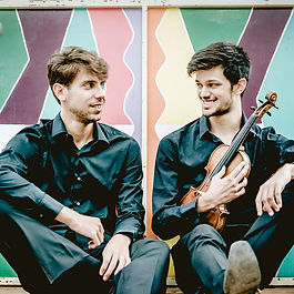 Il Duo Sabatini-Rugani (Daniele Sabatini, violino, e Simone Rugani, pianoforte) è un ensemble poliedrico, dedito sin dalla sua nascita a condividere col pubblico la sua passione per la musica da camera, con uno spiccato interesse per la musica contemporanea.

 

Si sono esibiti in numerose sale prestigiose, tra cui l’Edsberg Slott a Stoccolma, l’Edinburgh Society of Musicians, l’ORF Radiokulturhaus a Vienna, l’Archdiocese of Glasgow, il Palazzo dei Granduchi di Lituania a Vilnius. Sono stati più volte invitati a suonare a New York, presso la Casa Italiana Zerilli-Marimò della New York University, all’Istituto italiano di Cultura e in collaborazione con il Consolato Generale di Lituania.

 

In Italia hanno tenuto concerti presso la Sala dei Giganti (Padova); al Teatro Argentina e Oratorio del Gonfalone (Roma); Ateneo Veneto (Venezia), Teatro Comunale di Ferrara, Teatro Lottagono (Bergamo) e si sono esibiti per festival e associazioni musicali quali Roma Tre Orchestra, MusicaInsieme Bologna, Divertimento Ensemble (Milano), Torino Chamber Music Festival, Lunigiana International Music Festival, Campus delle Arti, Asiago Festival, MoMùs Padova – Barco Teatro e Maggio della grande musica a Cantù. Recentemente, sotto la direzione di Sieva Borzak, hanno eseguito il doppio concerto di Mendelssohn con l’Orchestra Roma Sinfonietta.

 

Il Duo ha vinto premi in numerosi concorsi internazionali di musica da camera, i più recenti includono: l’VIII Concorso internazionale Stasys Vainiunas a Vilnius (2° premio, con primo non assegnato); Concorso internazionale musicale “Città di Pesaro” (1° premio); Concorso di musica da camera “Città di Magliano Sabina” (1° premio e Premio Speciale Avos Chamber Music); Concorso “Francesco Cilea” (2° premio con primo non assegnato, e Premio del pubblico) e il Premio speciale per la migliore esecuzione di un brano di Gottfried Von Einem nell'ambito del Festival ISA 2018 organizzato dall' Università MDW (Vienna). Durante il periodo di lockdown per il coronavirus il Duo è stato più volte premiato in concorsi online, vincendo il contest #iorestoacasa e #suonoperte di Divertimento Ensemble e la registrazione di un CD al Lunigiana International Music Festival Awards.

Gli è stato inoltre assegnato il 27.mo Premio “Boris Christoff”, assegnato ogni anno ad un musicista od una formazione musicale di spicco alla memoria del celebre basso bulgaro. 

 

Daniele e Simone amano scoprire musica nuova ed esplorare repertori meno conosciuti. Recentemente si sono dedicati alla divulgazione della musica italiana del XX secolo, eseguendo regolarmente opere di Niccolò Castiglioni, Aldo Finzi, Gino Contilli e Silvio Omizzolo. Affascinati dalla musica del compositore russo Alfred Schnittke, ne hanno registrato la prima sonata e sono stati invitati ad eseguirne il Quartetto con pianoforte all’Asiago Festival con il violista Duccio Beluffi e il violoncellista Claudio Pasceri. In collaborazione con il Divertimento Ensemble, hanno inoltre partecipato ad una serie di concerti dedicati alla musica di Mauricio Kagel e di Salvatore Sciarrino, alla cui presenza hanno eseguito la Sonatina per violino e pianoforte. È stato inoltre dedicato loro il brano “Libero di essere niente più di un numero” di Maria Vincenza Cabizza, compositrice in residence della Biennale College di Venezia.

 

Dal momento della sua fondazione nel 2013, il Duo studia sotto la guida dei maestri Marco Fiorentini e Laura Pietrocini (membri fondatori dell’Ars Trio di Roma), e si perfeziona con Kostantin Bogino, Evgenia Epshtein e Maria Grazia Bellocchio. Daniele e Simone hanno inoltre conseguito il diploma di biennio specialistico in musica da camera presso il Conservatorio Santa Cecilia di Roma sotto la guida del maestro Roberto Galletto con la votazione di 110, lode e menzione ad honorem. Al momento frequentano il corso di Alto Perfezionamento in musica da camera dell’accademia Santa Cecilia di Roma con il maestro Ivan Rabaglia.

 

Per due anni consecutivi il Duo Sabatini-Rugani è stato invitato a partecipare all’International Summer Academy (ISA) del MDW, dove ha avuto l’onore di lavorare in stretto contatto con maestri come Hatto Beyerle, Avedis Kouyoumdjian, Johannes Meissl, Patrick Jüdt e Vida Vujic. Questa esperienza ha profondamente ispirato il Duo e lo ha spinto a scavare a fondo nelle partiture per affinare tutte le sfaccettature dell’esecuzione, nella convinzione che le connessioni che si creano e le storie che si narrano mentre si fa musica insieme abbiano un potere elettrizzante di coesione e comunione, e riescano a creare ponti tra culture diverse, in un’epoca in cui le nostre società appaiono sempre più frammentate.