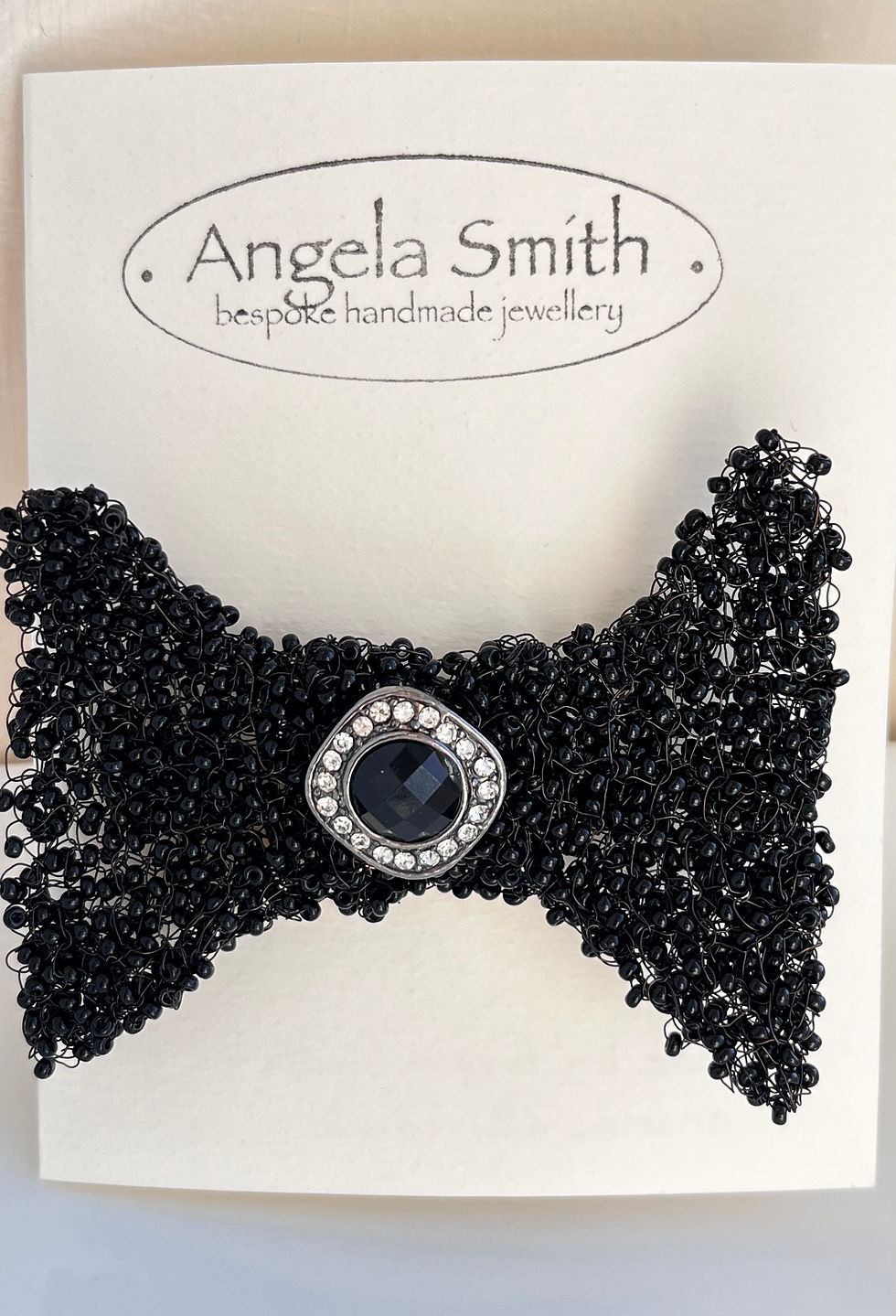 Knitted black wire and glass bead bow tie brooch
