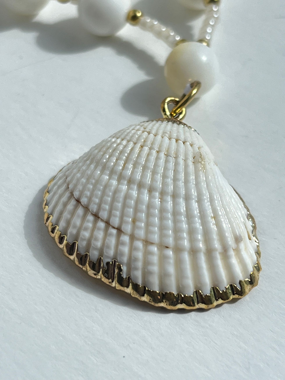 Thumbnail: Golden edged shell on a string of Mother of Pearl beads