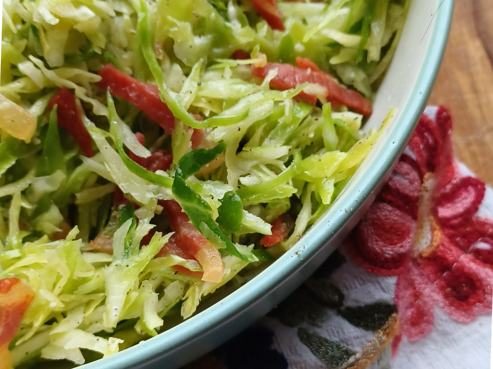 Cabbage salad with slices of Speck in a white bowl