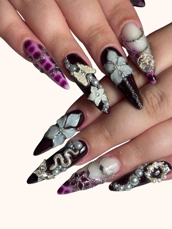 Extravagante Stiletto-Nägel in Dunkelrot, Weiss und Lila mit 3D-Blumen, Schmuckelementen, wie Ketten und Perlen im Nagelstudio in Zürich