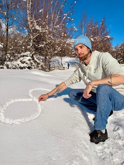 Yoann le fondateur de la marque dessinant le logo dans la neige à Crans-Montana portant un bonnet de la marque infinitytravel.ch
