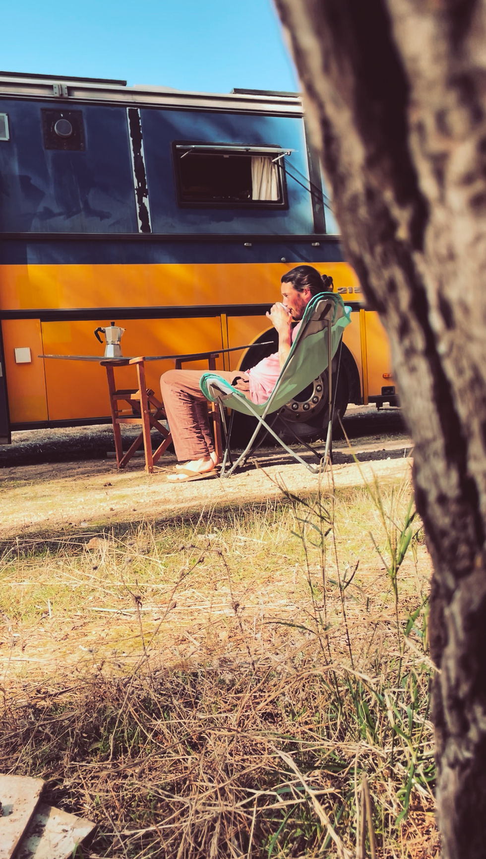 Yoann entrain de boire un café devant son bus aménagé durant l'un des roadtrip de sa vie nomade