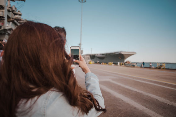 Family photographing arriving ship at Norfolk Naval Station military homecoming