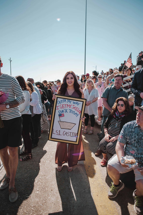 Families holding welcome home signs at Naval Station Norfolk arrival